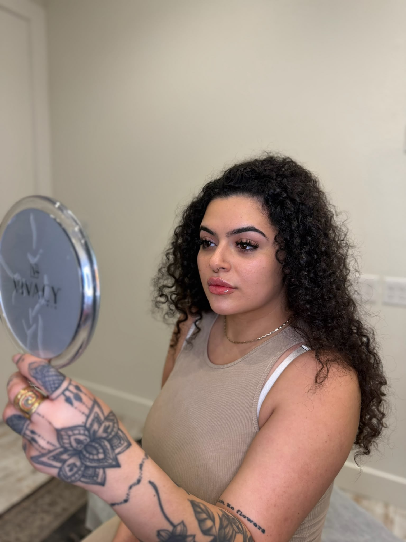 Client reviewing lip filler treatment with a hand mirror